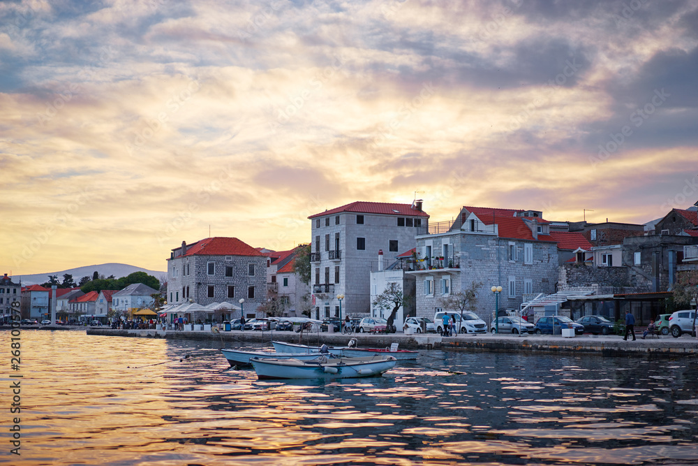 Beautiful sunset landscape. Fishing boat moored on Kastel coast in Dalmatia,Croatia.Old town near Adriatic sea.