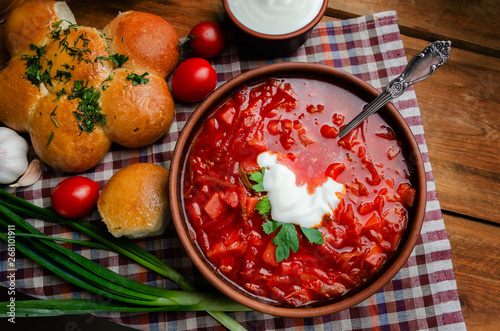 Ukrainian national cuisine - red borsch with donuts in a clay bowl on a wooden table.