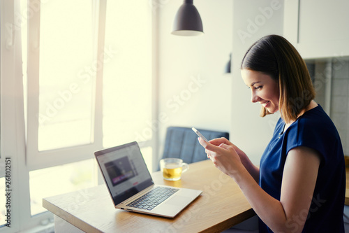 Working at home. Freelance concept. Business and technology. Pretty young woman using smartphone at home. © luengo_ua
