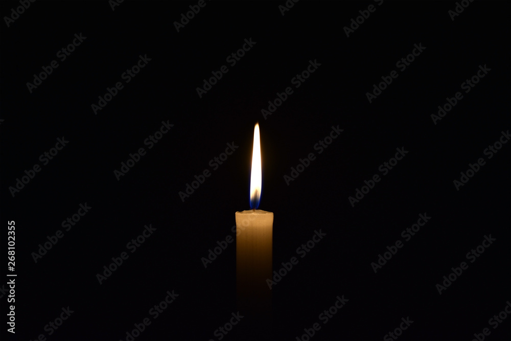 Candle burning in the black background. Located on the center of the shot. Candle burning in the black background. Located on the center of the shot.