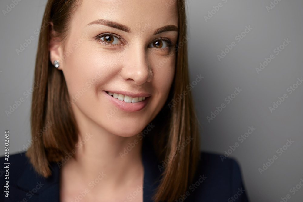 Close up studio portrait of oung businesswoman in suit looking at camera. Grey background. Close up studio portrait of oung businesswoman in suit looking at camera. Grey background.