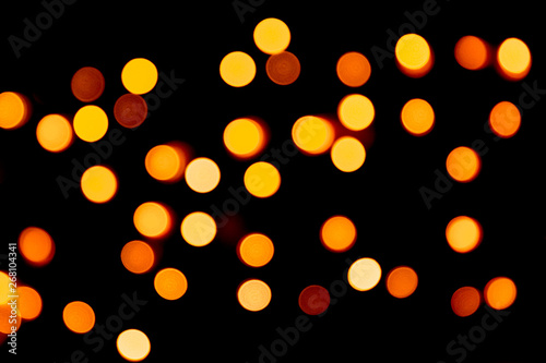 Holiday glowing gold backdrop. defocused and blurred many round yellow light on Christmas black background