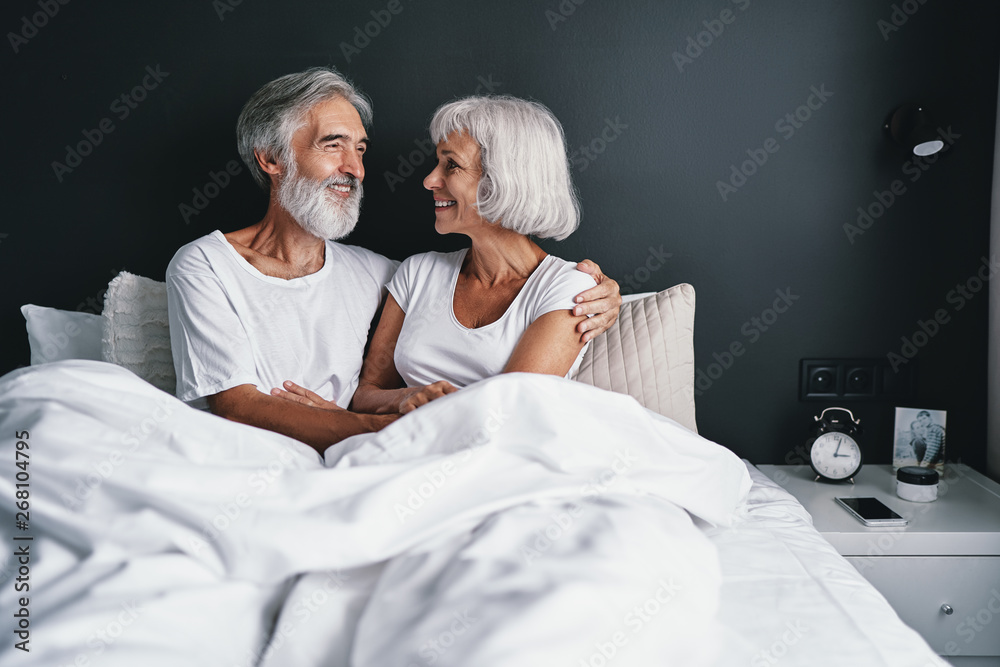 Happiness and tender. Senior family. Husbang hugging his wife in bed. - obrazy, fototapety, plakaty 