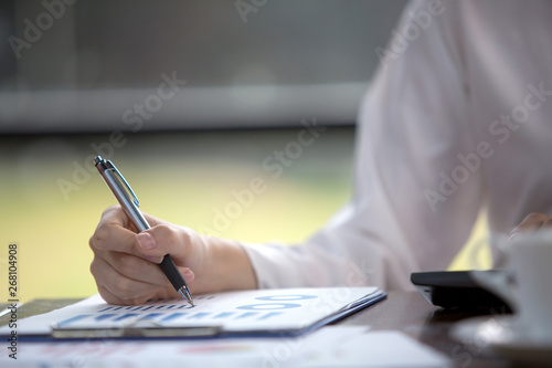 Close up Business women using calculator and writing make note with calculate about cost at home office.