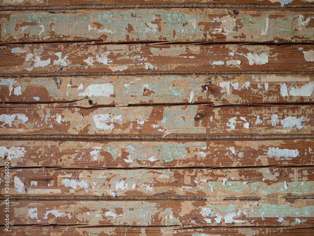Old wood wall in log house with pieces of wallpaper and newspapers Old wood wall in log house with pieces of wallpaper and newspapers