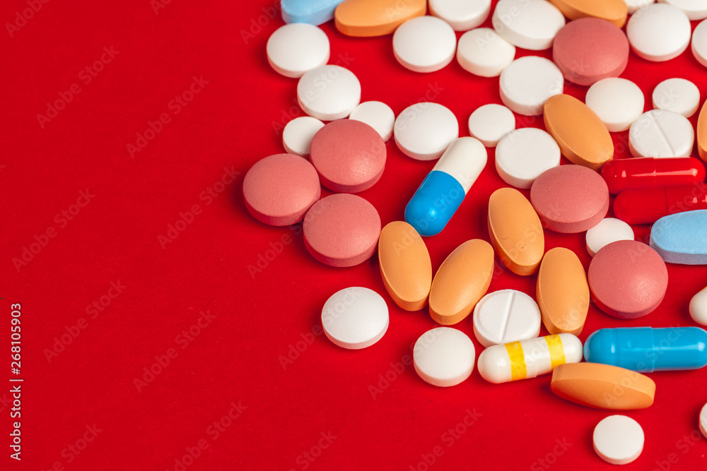 Many medicine pills close up on red background Many medicine pills close up on red background
