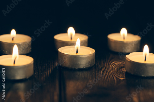 candles burning in darkness over black background. commemoration concept.