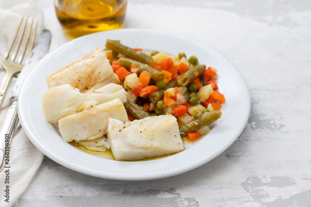 boiled cod fish with boiled vegetables on white plate on ceramic background boiled cod fish with boiled vegetables on white plate on ceramic background