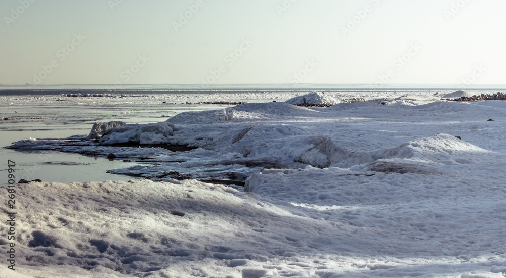 Snow pile, hill. Large snow drift isolated on a blue sky background, outdoor view of ice blocks at frozen finland lake in winter Snow pile, hill. Large snow drift isolated on a blue sky background, outdoor view of ice blocks at frozen finland lake in winter