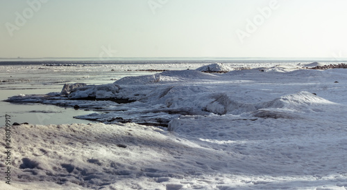 Snow pile, hill. Large snow drift isolated on a blue sky background, outdoor view of ice blocks at frozen finland lake in winter