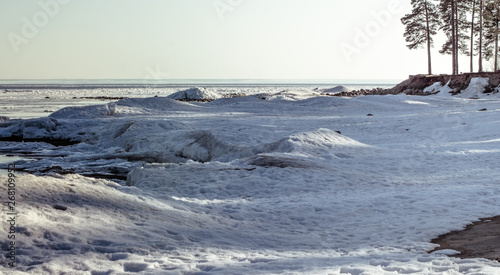 Snow pile, hill. Large snow drift isolated on a blue sky background,  outdoor view of ice blocks at frozen finland lake in winter