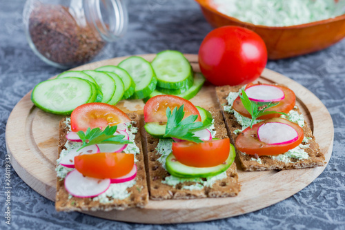 delicious diet sandwiches with cottage cheese with herbs and vegetables on a gray background