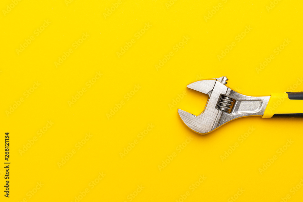 adjustable wrench with yellow handle on the yellow background