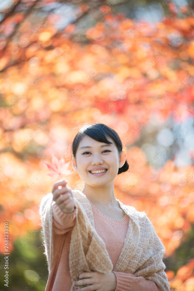 紅葉を持ち微笑む女性