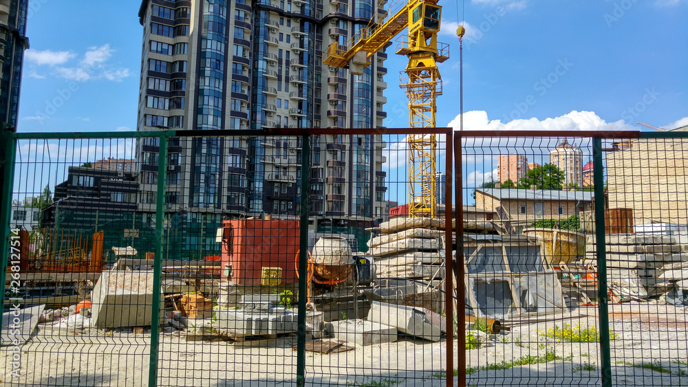 Image of modern building construction behind the wired fence at bright sunny day
