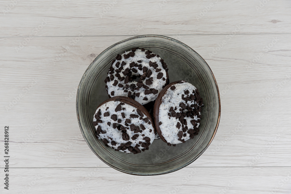 Donuts in a plate on white wood background, top view Donuts in a plate on white wood background, top view