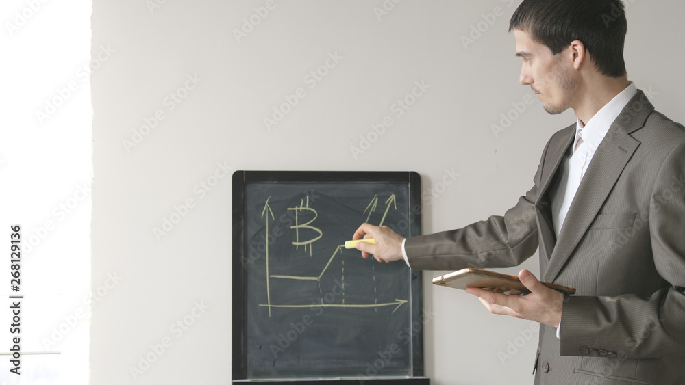 Creative young businessman in suit draws charts on board. Creative young businessman in suit draws charts on board.