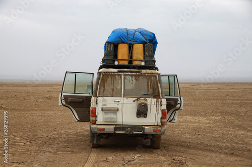 stojący samochód terenowy z otwartymi drzwiami podczas postoju na pustkowiu w pustynnym terenie © KOLA  STUDIO