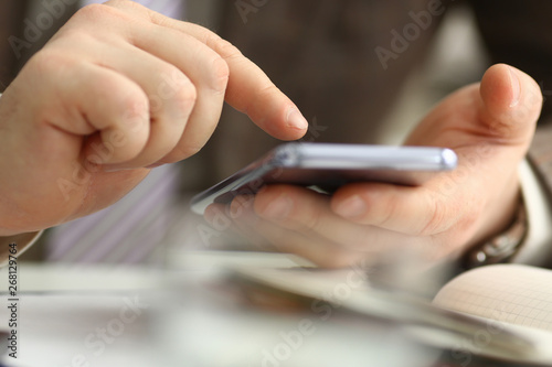 Male arm in suit hold phone and silver pen at workplace closeup. Read news mania send sms chat addict use electronic bank modern lifestyle job plan colleague share blog tweet web application search