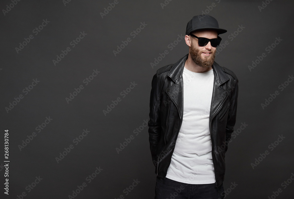 Hipster handsome male model with beard wearing white blank t-shirt and a baseball cap with space for your logo or design in casual urban style