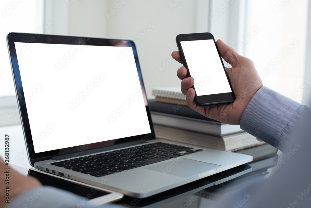 Mockup image of businessman using smartphone working on laptop Mockup image of businessman using smartphone working on laptop