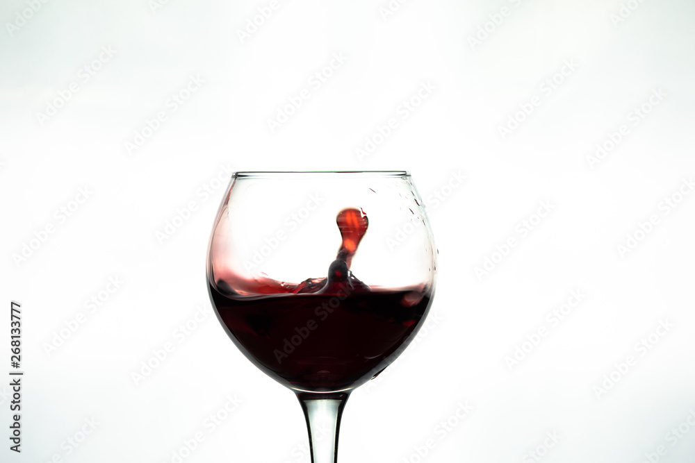 Red wine splash into glass on white background