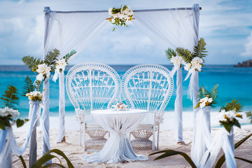 Beach wedding arch gazebo ceremonial decorated with white flowers on a tropical grand anse sand beach. Outdoor beach wedding setup. La Digue, Seychelles