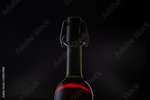 Rose wine. Red wine in bottle and metal opener on cork. Dark background