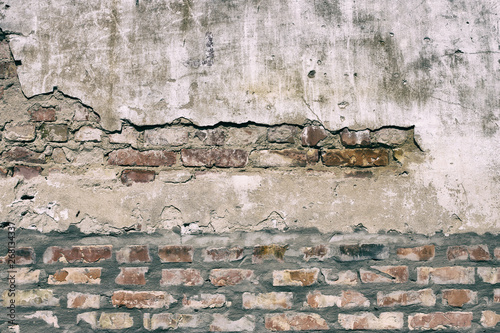 Old damaged brick wall with shabby plaster