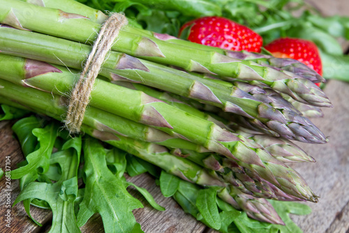 Grüner Spargel mit Rucola und Erdbeere auf einem Holztisch