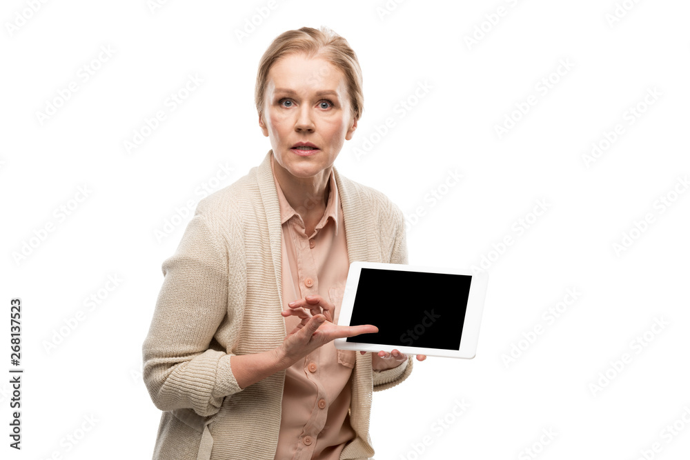confused middle aged woman pointing with finger at Digital Tablet with blank screen Isolated On White confused middle aged woman pointing with finger at Digital Tablet with blank screen Isolated On White