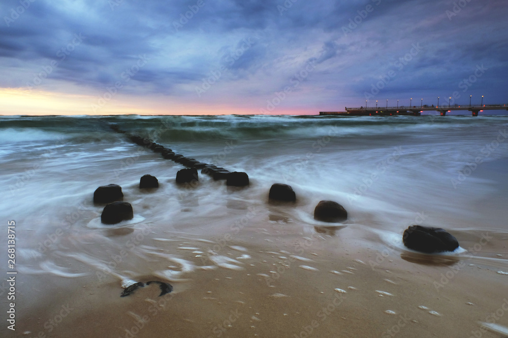 Fototapeta premium Zachód słońca na wybrzeżu Morza Bałtyckiego,molo w Kołobrzegu,Polska.