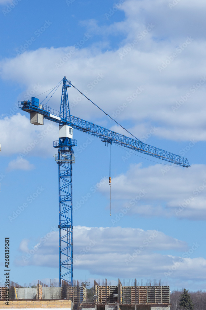 Construction crane unfinished building on background of cloudy sky. Construction of house, office center