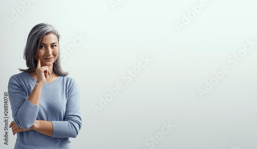 Asian woman smiling and pointing her finger to her cheek