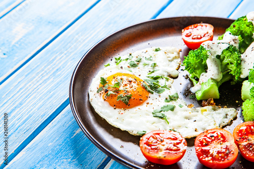 Fried egg with vegetables on wooden table