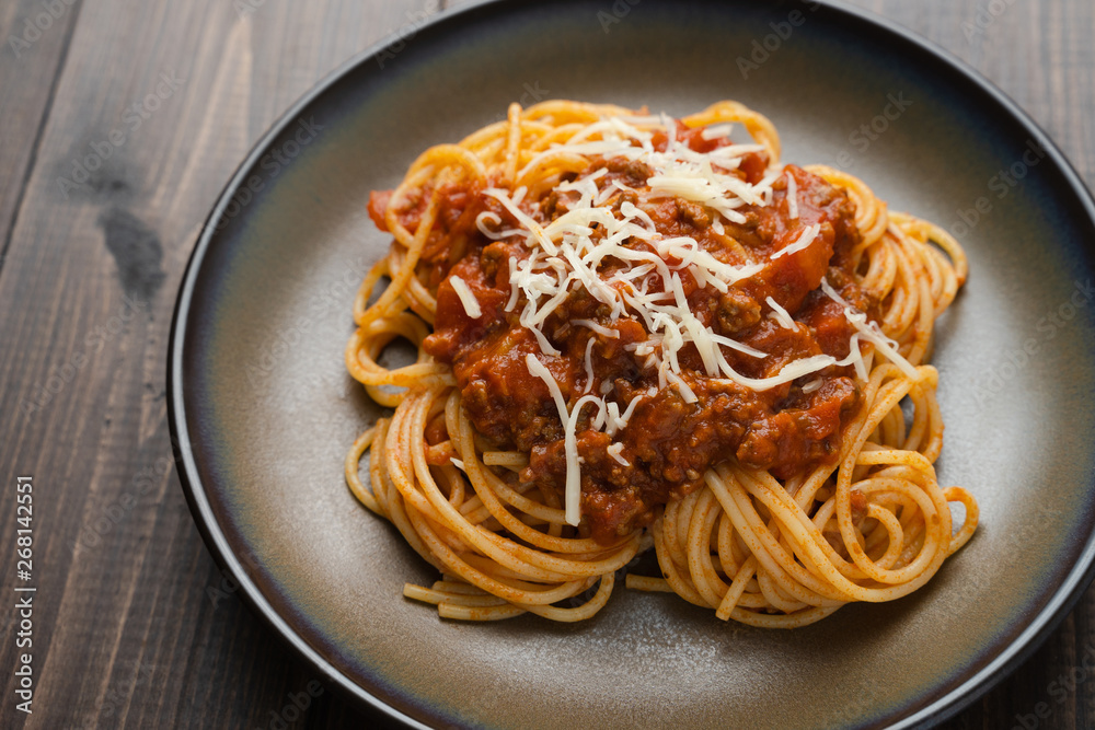 Spaghetti Bolognese sauce or tomato sauce on a dark wooden board, traditional Italian food closeup and top view Spaghetti Bolognese sauce or tomato sauce on a dark wooden board, traditional Italian food closeup and top view