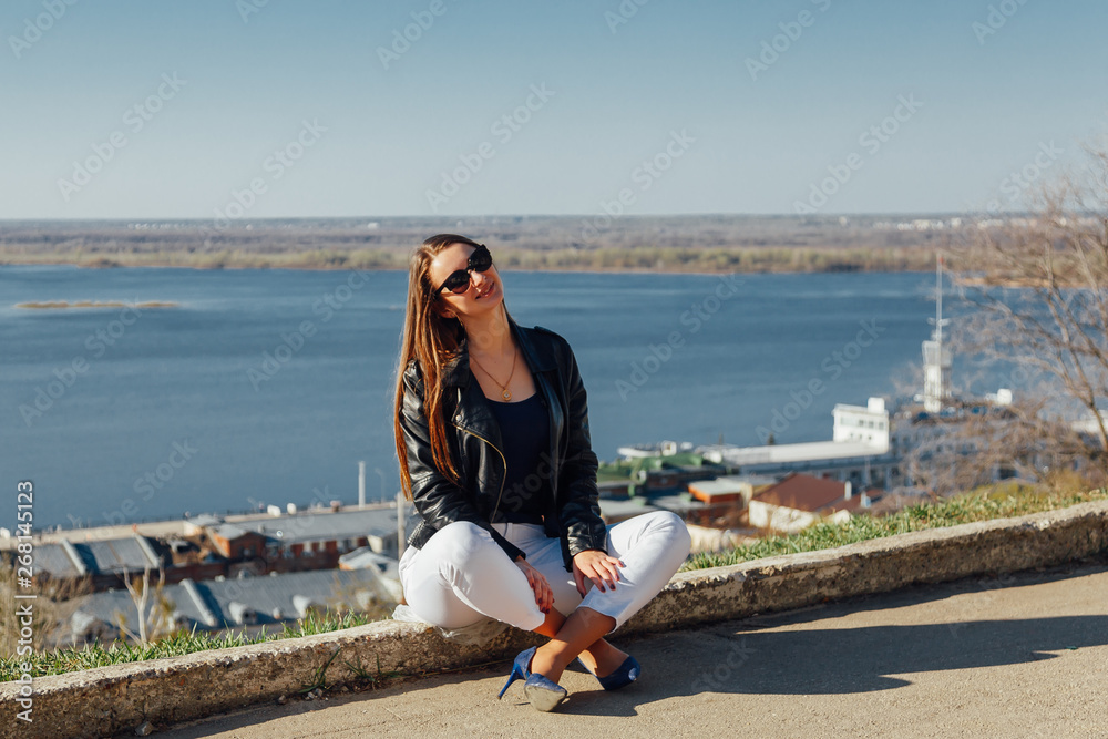 Young beautiful girl sits on a brick parapet