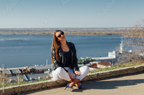 Young beautiful girl sits on a brick parapet
