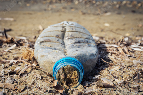 close up of plastic bottle filled with sand on the beach - plastic garbage in the sea