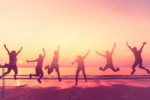Happy friend jumping at tropical sunset beach background.