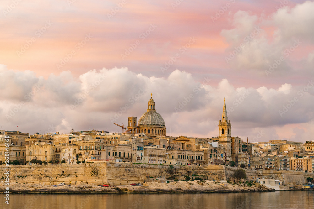 Skyline at beautiful sunrise from Sliema with churches of Our Lady of Mount Carmel and St. Paul's Anglican Pro-Cathedral. Panoramic view of Valletta city - the Capital of Malta.