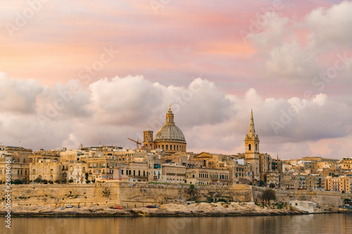 Skyline at beautiful sunrise from Sliema with churches of Our Lady of Mount Carmel and St. Paul's Anglican Pro-Cathedral. Panoramic view of Valletta city - the Capital of Malta.