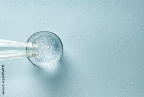 fresh drink water from the bottle and a glass of sparkling water on a turquoise modern empty background. space for text from above. web banner with copyspace