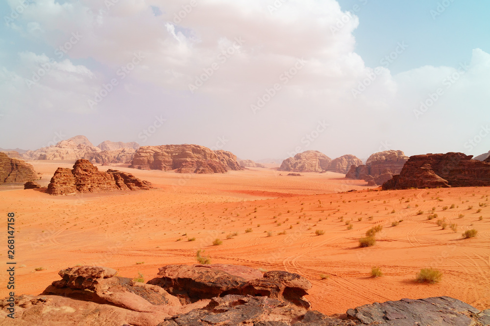 Wadi Rum desert, Jordan, The Valley of the Moon. Orange sand, haze, clouds. Designation as a UNESCO World Heritage Site. National park outdoors landscape. Offroad adventures travel background. Wadi Rum desert, Jordan, The Valley of the Moon. Orange sand, haze, clouds. Designation as a UNESCO World Heritage Site. National park outdoors landscape. Offroad adventures travel background.