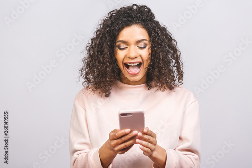 Portrait of african american cute attractive lovely cheerful optimistic wavy-haired girl using new device gadget isolated over white background.