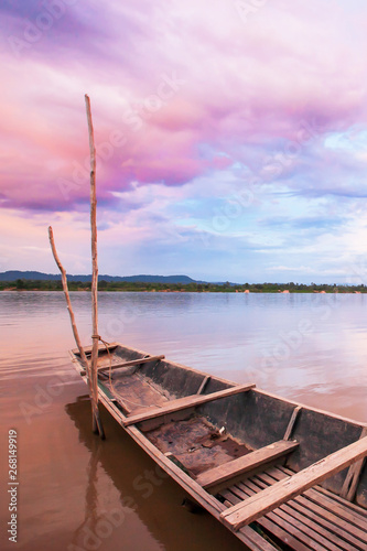 Fototapeta Naklejka Na Ścianę i Meble -  Dramatic clouds on the sunset sky over fishing boat on Mekong River.
