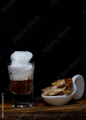 Coffee with foam in a small tube glass on a wood.