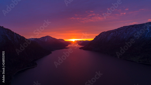 a magical sunset on a lake in the mountains. violet-orange bright dawn on a mountain lake. reflection of the beautiful sky in a mountain lake at sunset. Wallpapers and calendar. sunset in the mountain © Wlad Go