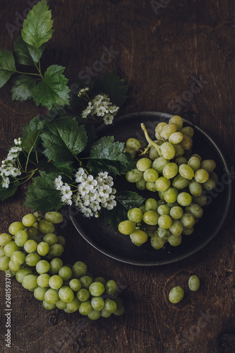 White Grapes served on Plate in a Dark Wooden Background, top view