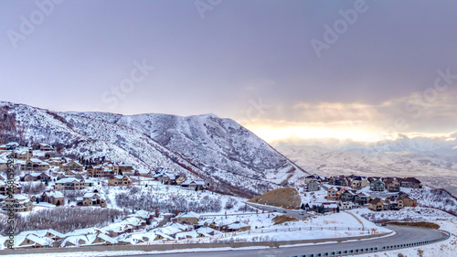 Clear Panorama Road curving along a mountain coated with snow against cloudy sky in winter